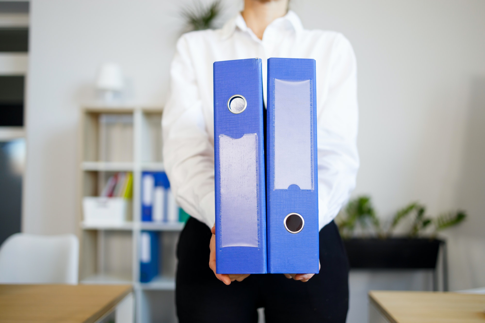 Secretary holds two blue folders with documents in her hands